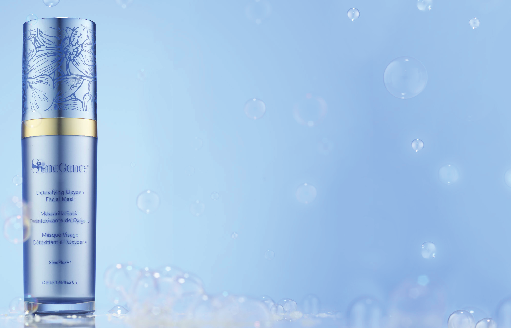 Detoxifying Oxygen Facial Mask in its periwinkle-blue bottle, with an orchid-engraved cap and gold band, rising from a drift of pale blue bubbles.