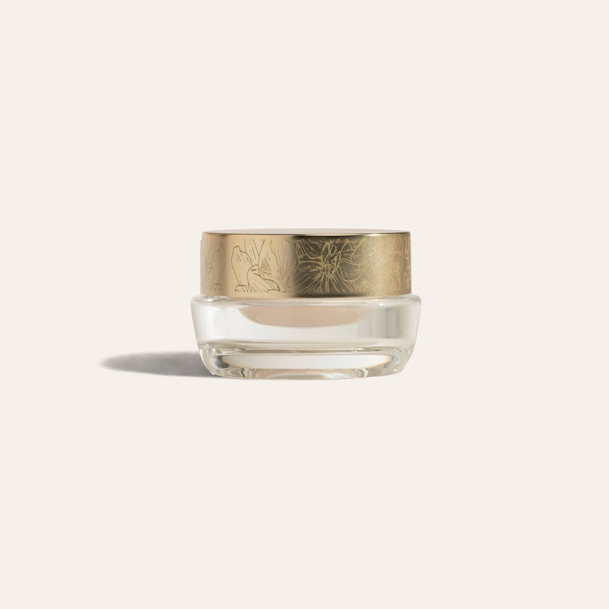 A clear jar of pale cream with an orchid-engraved gold lid, EyeCrème.