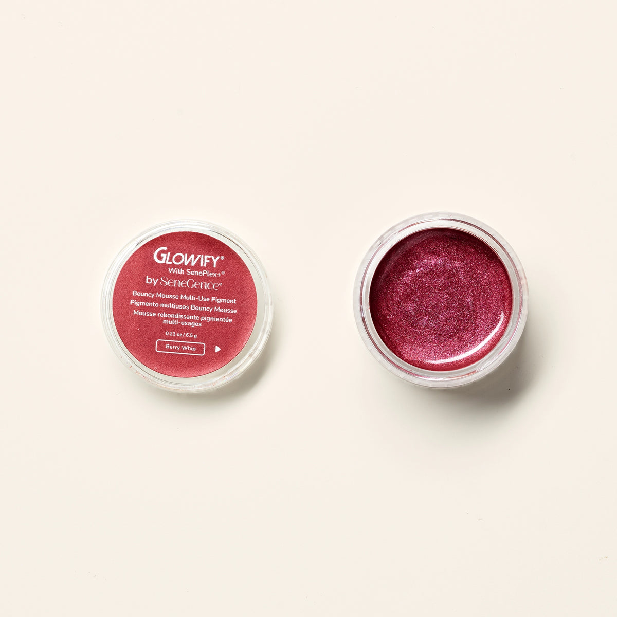 An open pot of shimmering berry pigment beside its labeled lid, Glowify Bouncy Mousse Multi-Use Pigment.