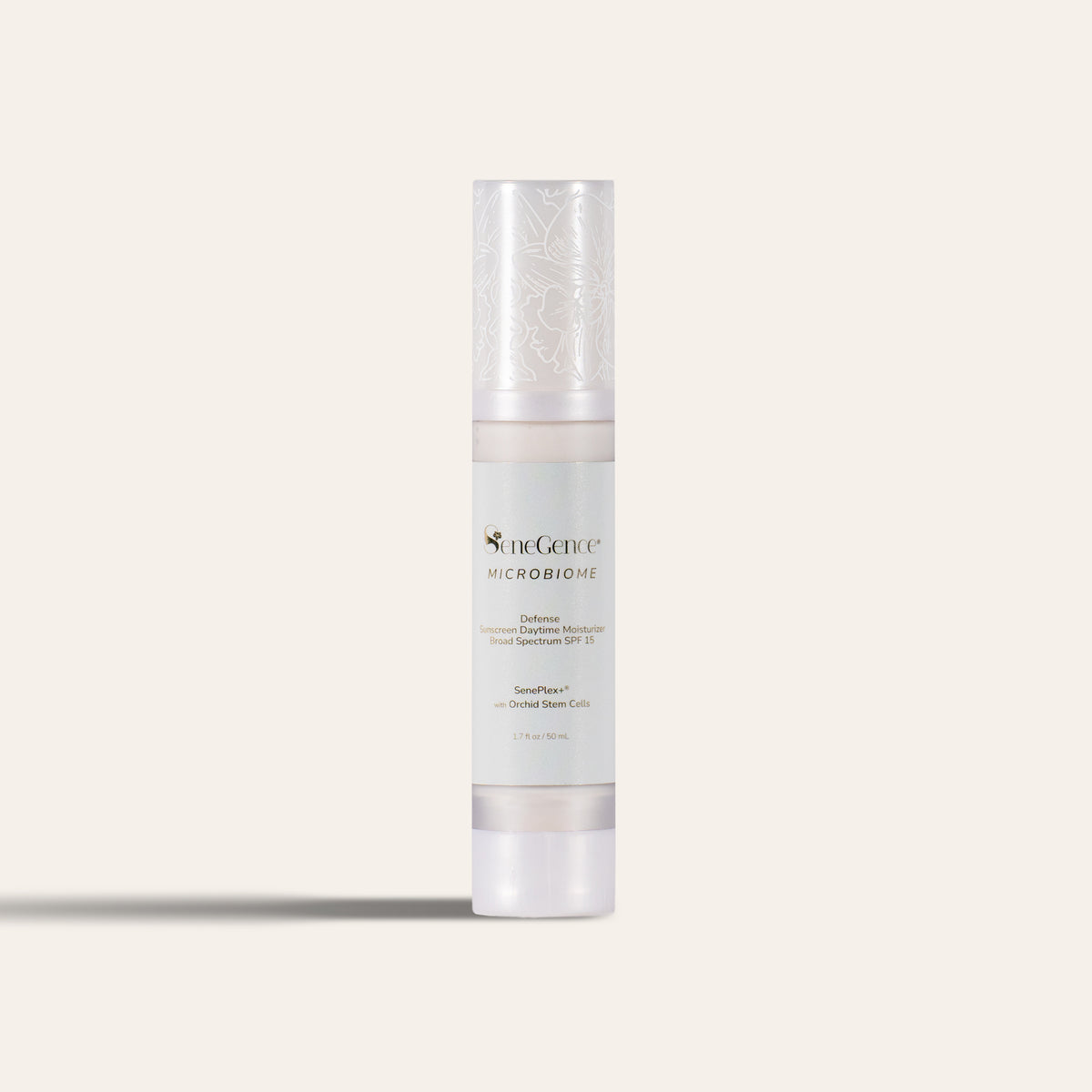 A slim airless bottle with a frosted pearl-white cap printed with white orchid line art, a pale mint-grey label with gold-tone text and a frosted white base, Microbiome Defense Daytime Moisturizer SPF 15.
