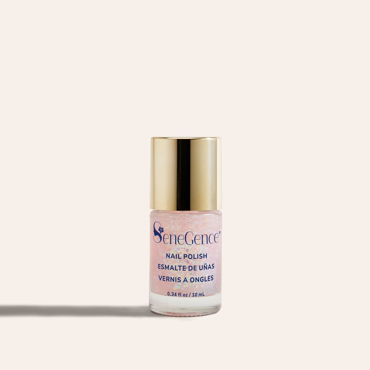 A clear bottle of sparkling pink nail polish with a gold cap, Sparkle & Sleigh Nail Polish.